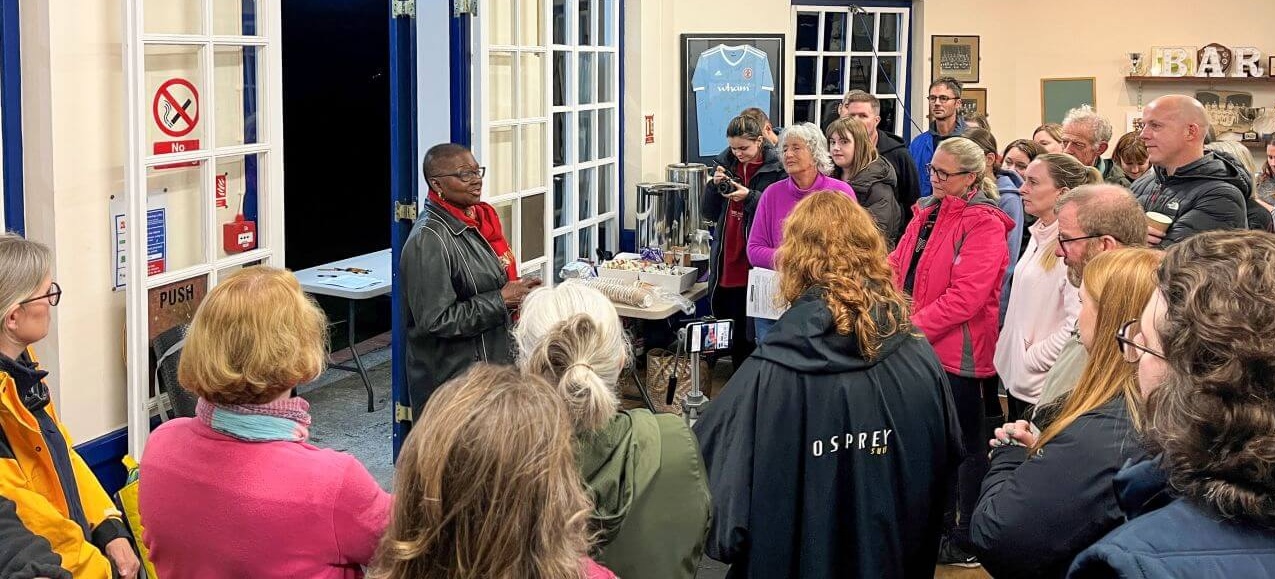 Sleepout 2024 participants watch a guest speaker indoors at the start of the evening